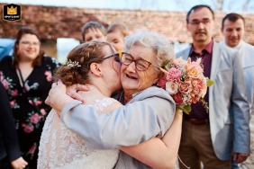 Grandma lovingly kisses the bride on the cheek against a backdrop of the picturesque Gruyère countryside, in a cherished moment filled with warmth and joy.